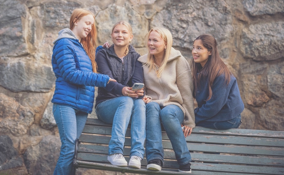 Fyra ungdomar som sitter på en bänk och pratar