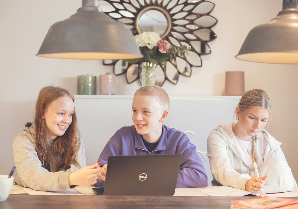 Tre ungdomar som sitter vid ett bord och pratar